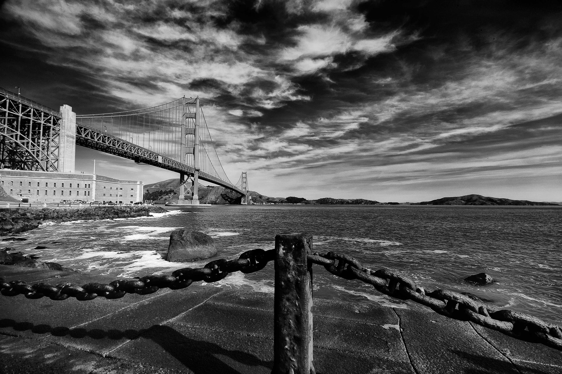 Golden Gate Bridge under dramatic clouds in black and white