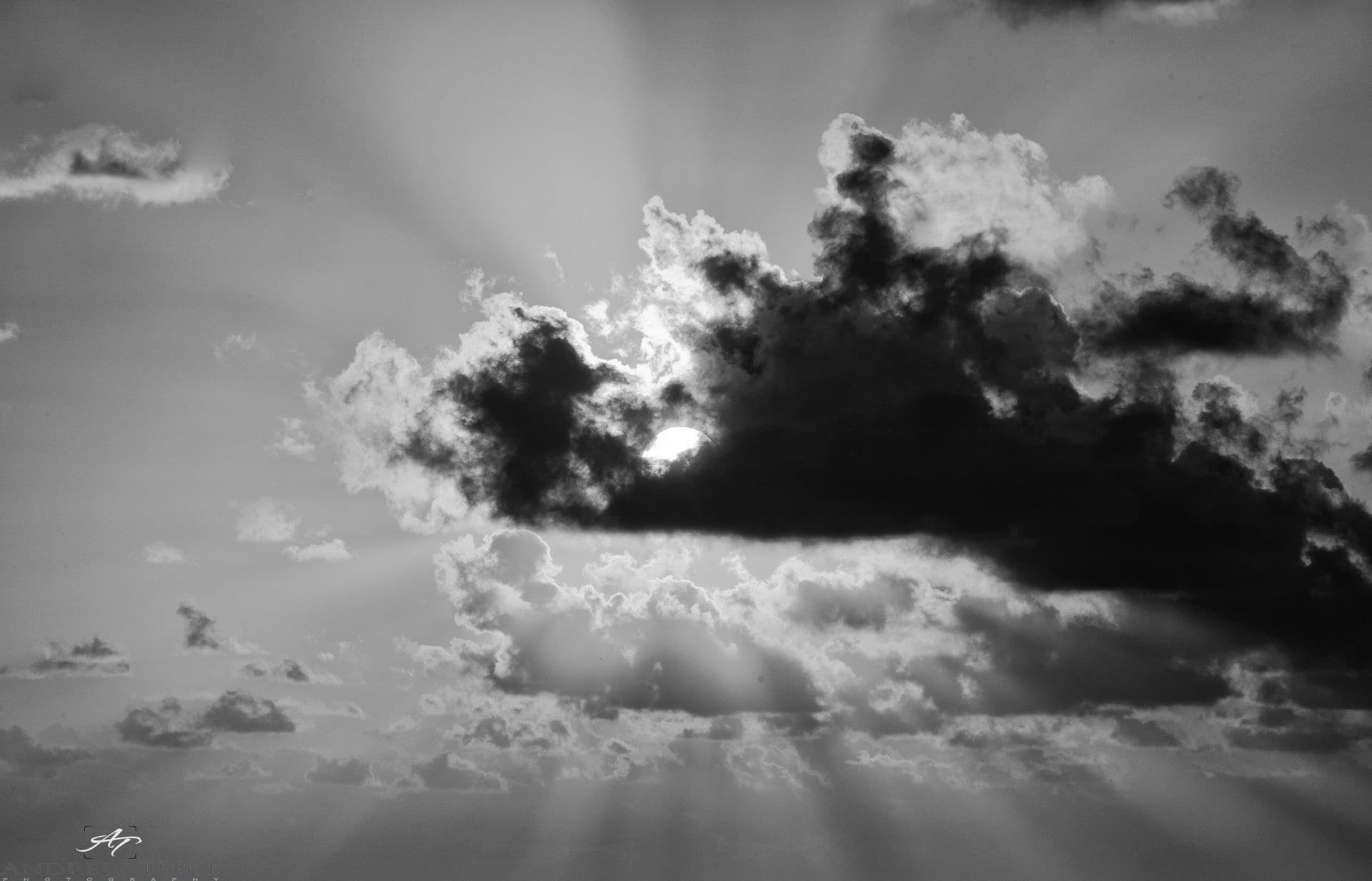Sun breaking through a dense cloud bank, sending rays across the sky